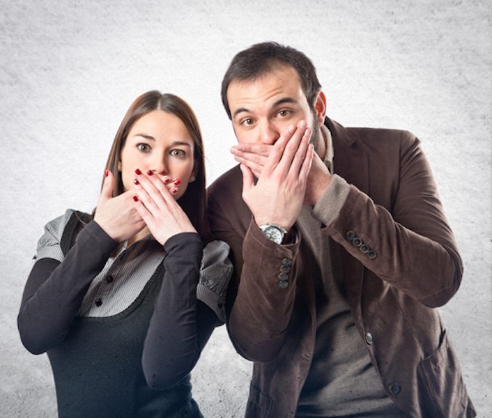 Couple has hands over their mouth so that they don't say the wrong things to a home buyer while selling their house