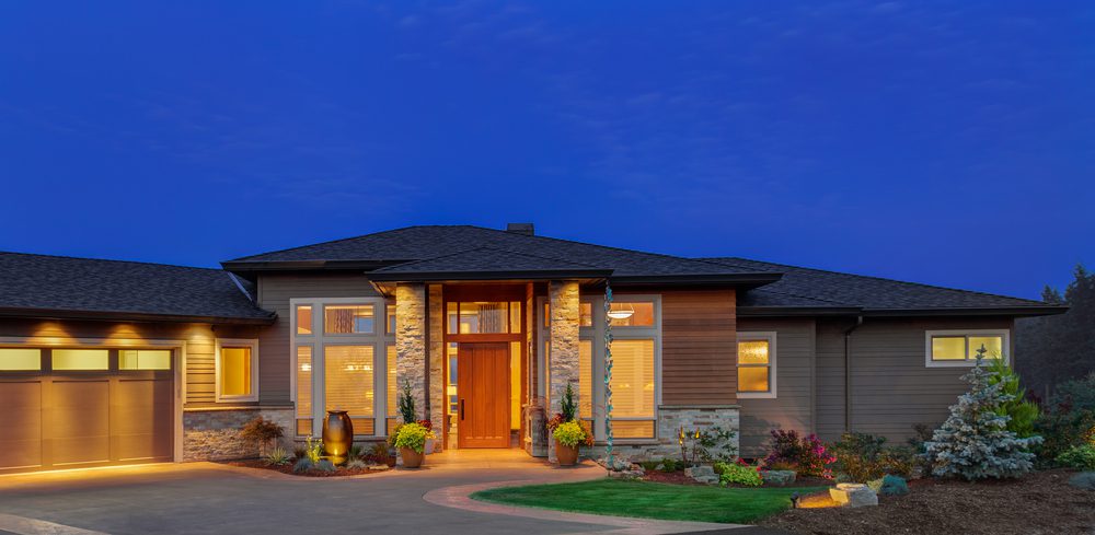 Single Story large home is lit up against blue sky