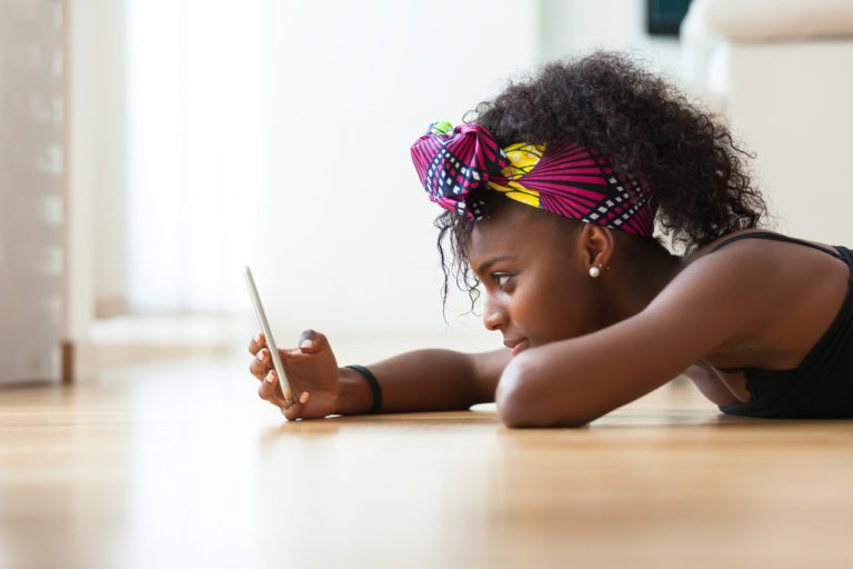 High School Girl on the floor with her cell phone at home