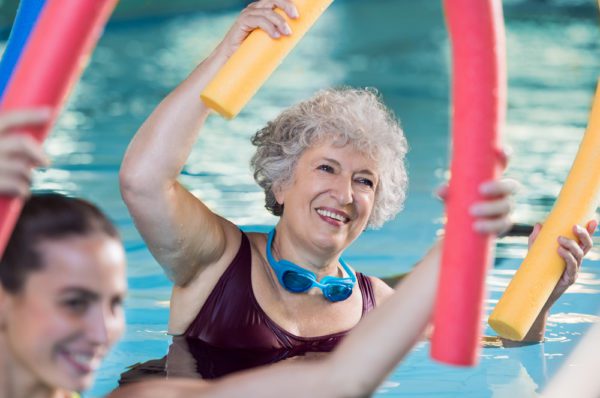 A woman does water aerobics at the 55+ senior community swimming pool