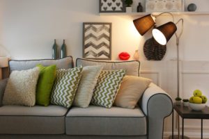 Couch with Green and Grey Pillows, Brown Lamp and Wall hangings