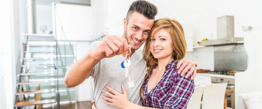 smiling couple embrace as they hold up keys to new home in Las Vegas