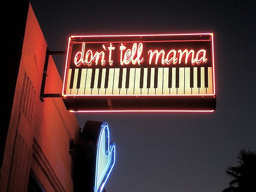 Sign outside of Don't tell mama Karaoke bar is lit up with pieano keys