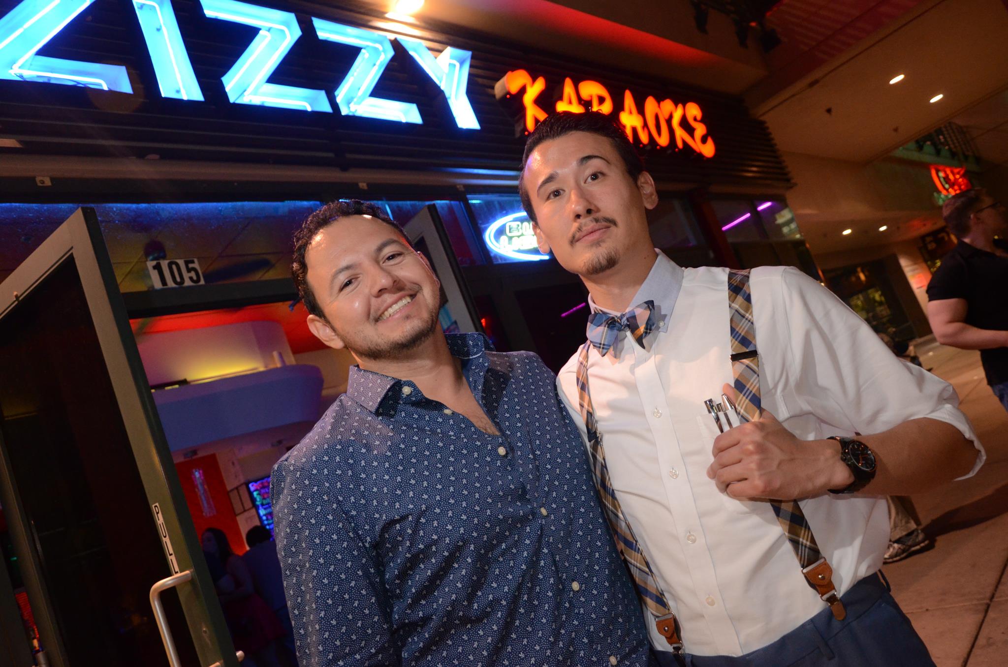 Two men stand outside of Zizzy Karaoke Bar Las Vegas and are smiling, one has thumb up