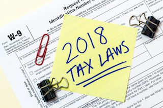 Yellow post it note says 2018 Tax Laws and is stuck on a tax form