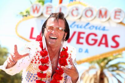 Elvis is standing outside of the Las Vegas sign