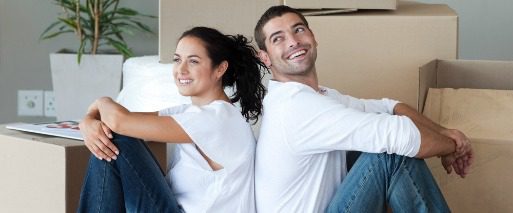 Happy couple sitting in front of boxes