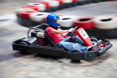 Boy in a red shirt and blue helmet is in a go kart numbered 3 similar to what they would have at the Las Vegas Mini Gran Prix