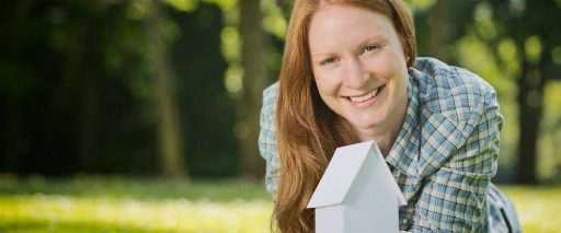 smiling woman holding small white house