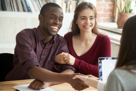 smiling man and woman shaking the hand of a real estate agent